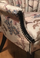 Closeup of arm of upholstered armchair with Asian inspired fabric