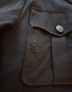 Leaf motif embroidered with black floss on black gabardine